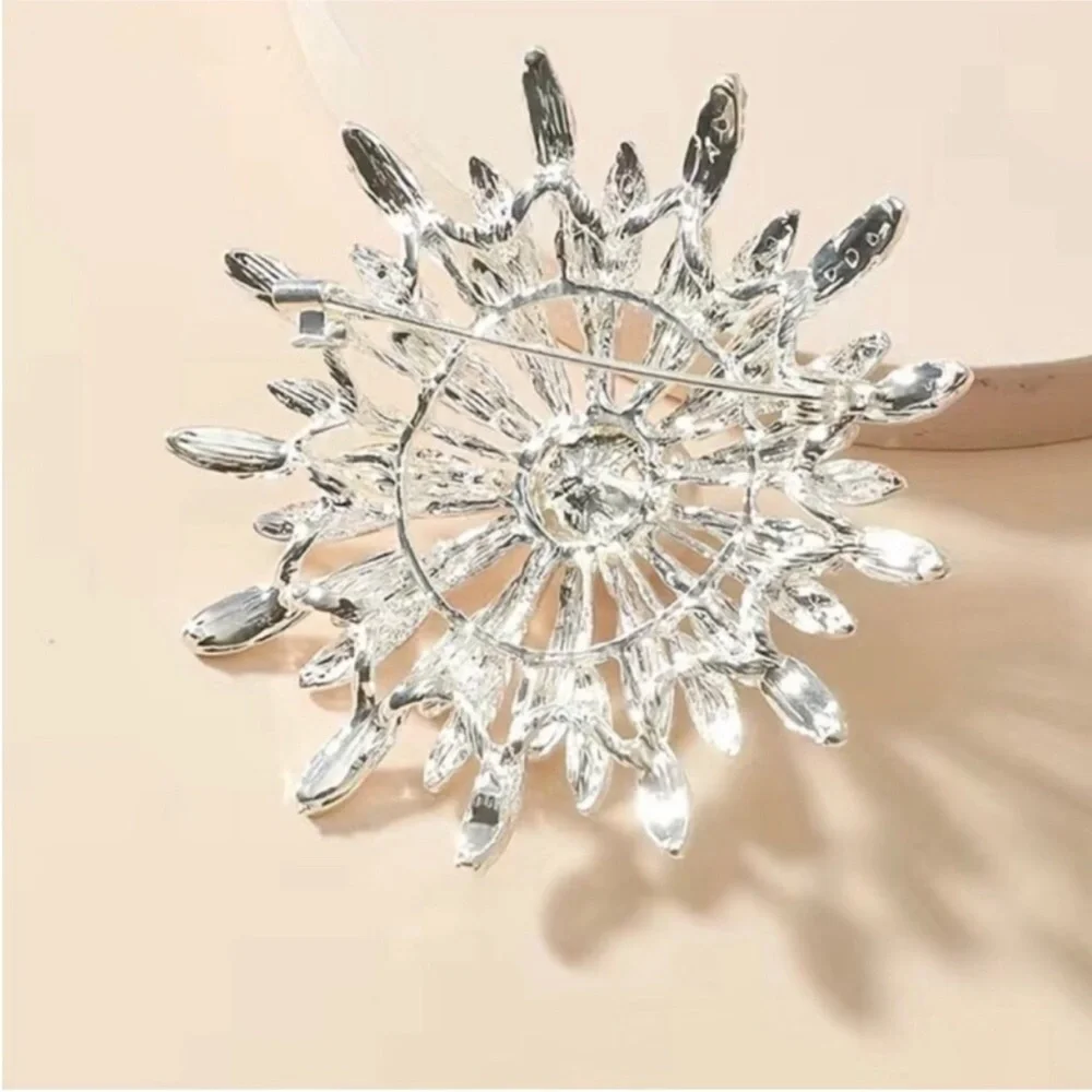 New silver-toned sunburst brooch clear rhinestones and a central faux pearl